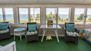 Une pièce meublée de meubles en osier, avec une petite table et une vue sur la mer.