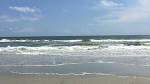 A beach with waves crashing onto the shore under a clear sky.