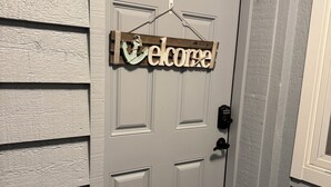 A white door with a 'Welcome' sign above it.