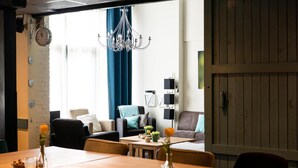 Een moderne woonkamer met een eethoek, met een kroonluchter, banken en een houten eettafel.