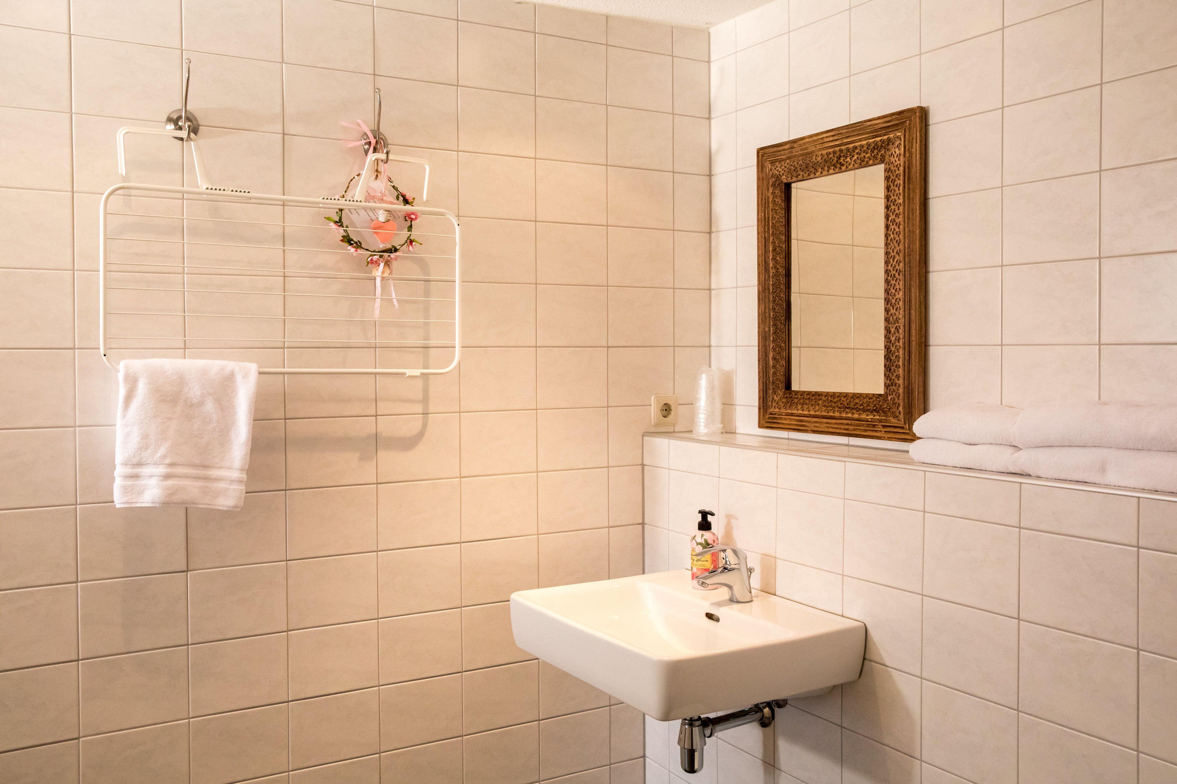 Un baño con lavamanos blanco, un espejo y un toallero decorado con motivos florales.