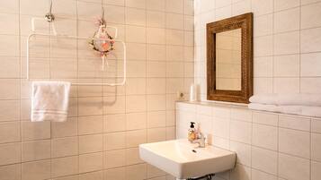 Un baño con lavamanos blanco, un espejo y un toallero decorado con motivos florales.