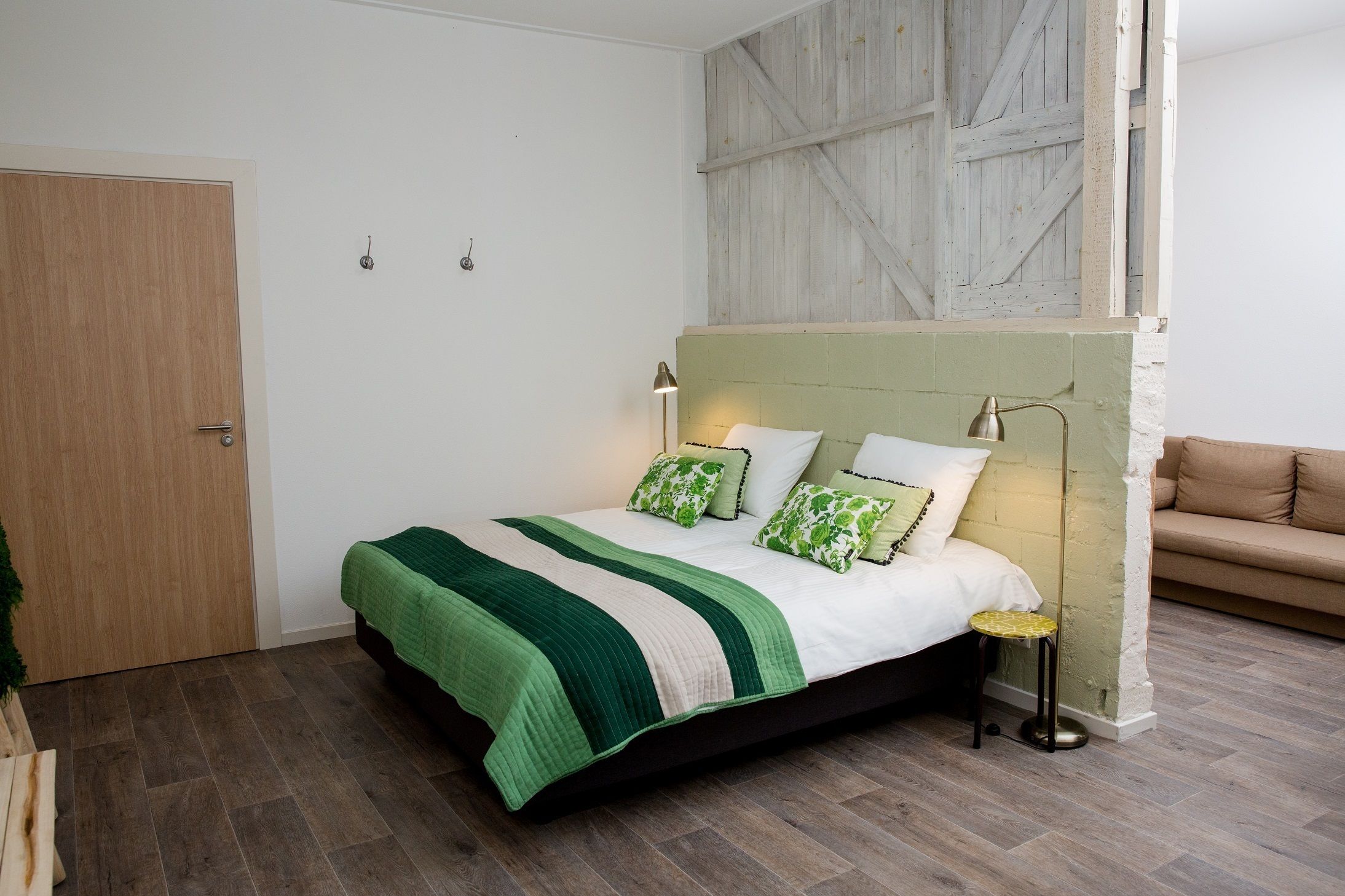 A bedroom with a bed, bedside lamps, a green and white striped bedspread, and a green and white patterned pillow.