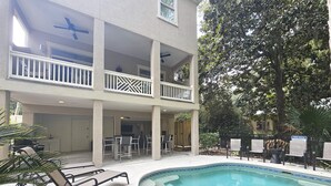 A two-story building with a pool, outdoor seating, and a covered patio area.