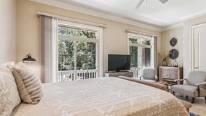 A bedroom with a large bed, a television, a chair, and a desk.