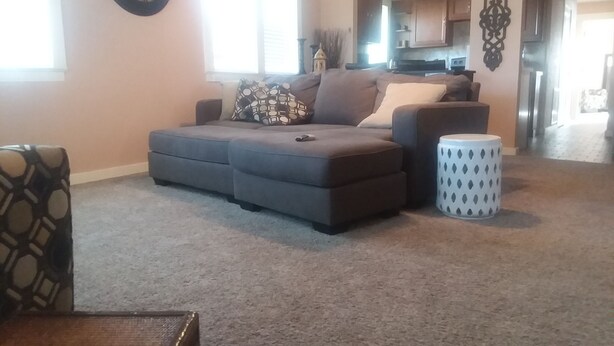 A living room with a sectional sofa, a patterned armchair, and a small ottoman. - 3 Bedroom 2 Bath Bungalow  (Mountain Grove)