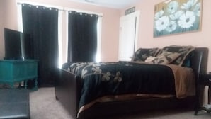 A bedroom with a bed, a chair, a television, and a painting on the wall. - 3 Bedroom 2 Bath Bungalow  (Mountain Grove)