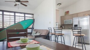 Une cuisine moderne avec un coin repas, un ventilateur de plafond et une grande fenêtre équipée de stores.