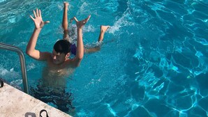 Une piscine dont le bord est recouvert de carreaux et qui est équipée d’une échelle en métal.