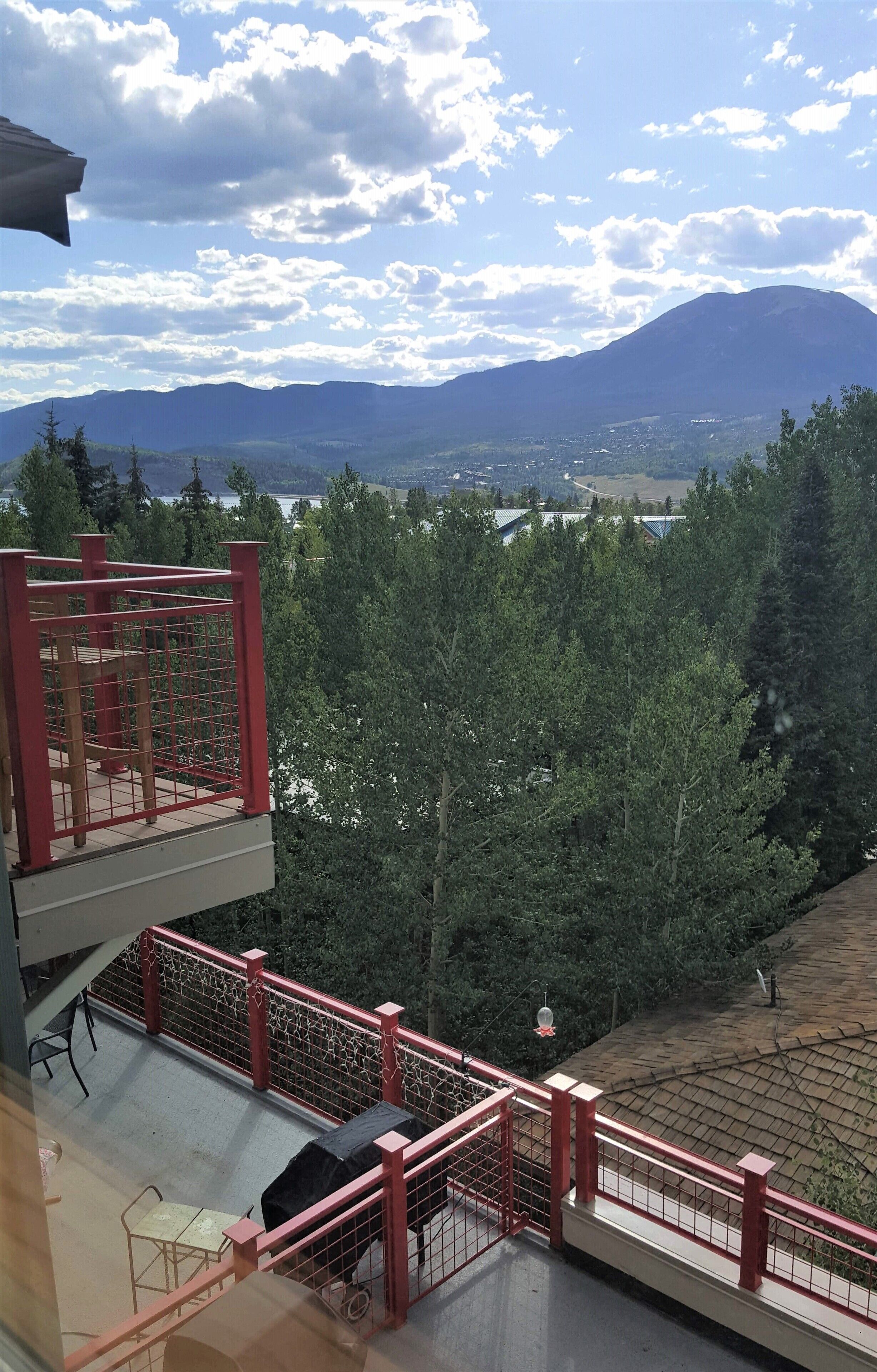 Un balcon avec une balustrade rouge donnant sur un paysage montagneux.