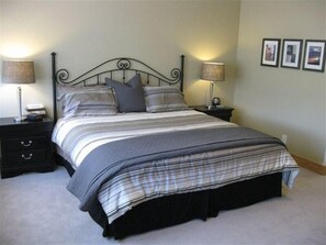 A neatly made bed with a striped bedspread and pillows, flanked by two bedside tables with lamps, in a room with a plain wall and framed pictures. - Spacious Two Level Condo, Lake Dillon 3 Blocks Away (Dillon)