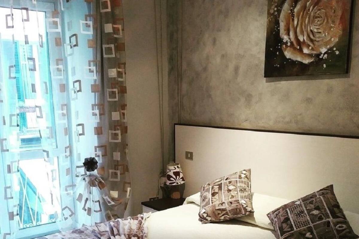 Une chambre à coucher avec un lit, des oreillers, une lampe et un tableau accroché au mur.