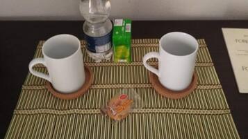 Un tavolo con due tazze bianche su sottobicchieri, una bottiglia d'acqua e una bustina di tè.