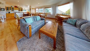A spacious living area with a sofa set, a coffee table, and a dining table with chairs.