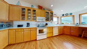A kitchen with wooden cabinets, a microwave, a stove, a coffee maker, and a dishwasher.