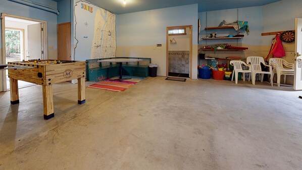 Una habitación con una mesa de fútbol de mesa, un mapa en la pared y una puerta que da a otra estancia.