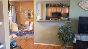 A living room with a dining area, a kitchen with wooden cabinets, a microwave, and a television.