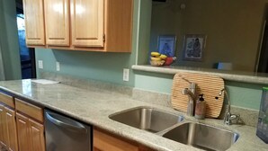 A kitchen with wooden cabinets, a stainless steel sink, and a wooden cutting board.