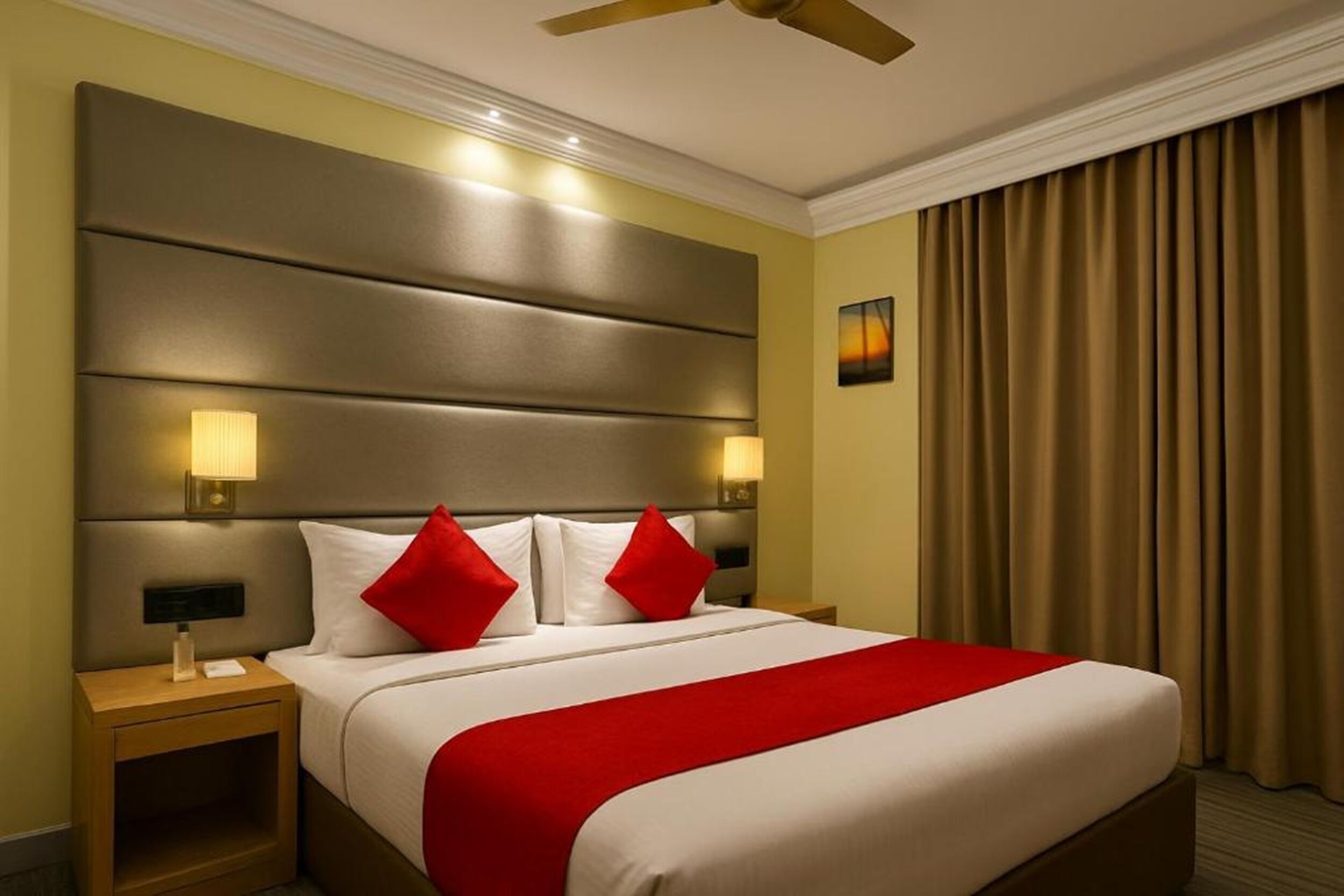 Una habitación de hotel con una cama grande, dos lámparas de noche, un ventilador de techo y vistas al exterior a través de cortinas.