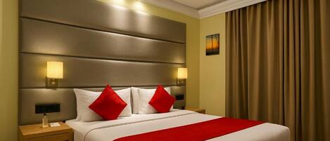 Una habitación de hotel con una cama grande, dos lámparas de noche, un ventilador de techo y vistas al exterior a través de cortinas.