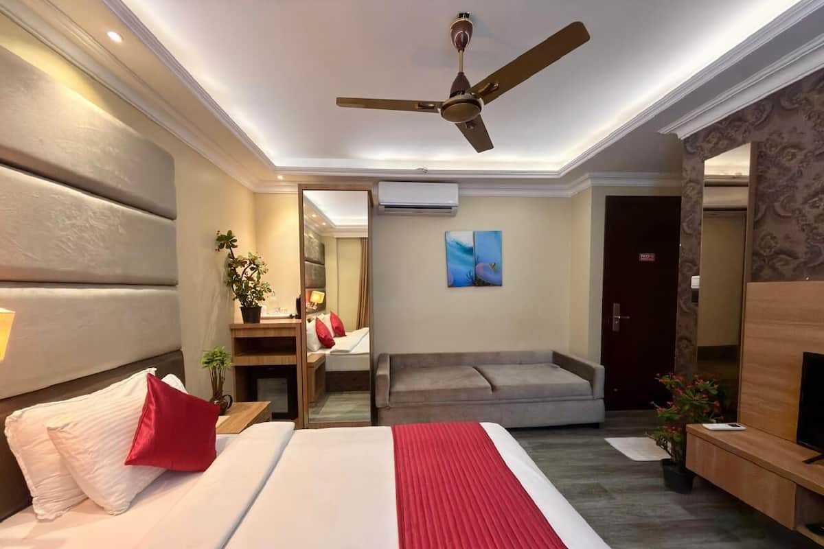 Quarto de hotel com cama, sofá, televisão e ventoinha no teto.