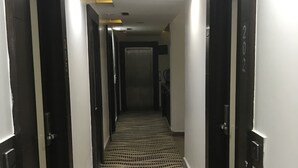 Passadís d'hotel amb un disseny de moqueta negre i blanc, portes negres i il·luminació empotrada.