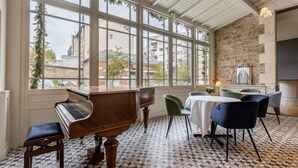 Un piano dans une pièce dotée de grandes fenêtres et d’un mur en pierre.