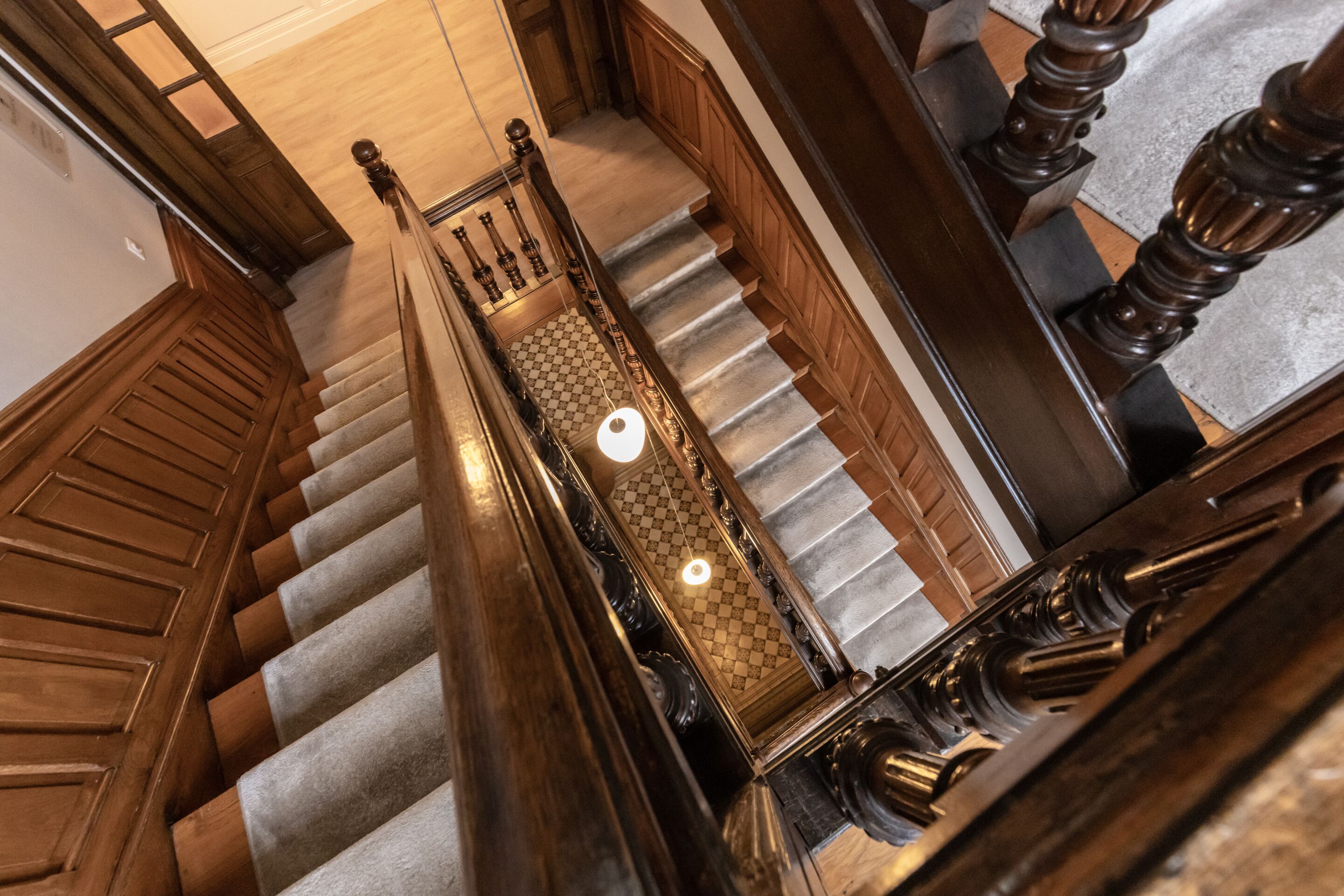 A grand staircase with wooden railings and a checkered carpet.
