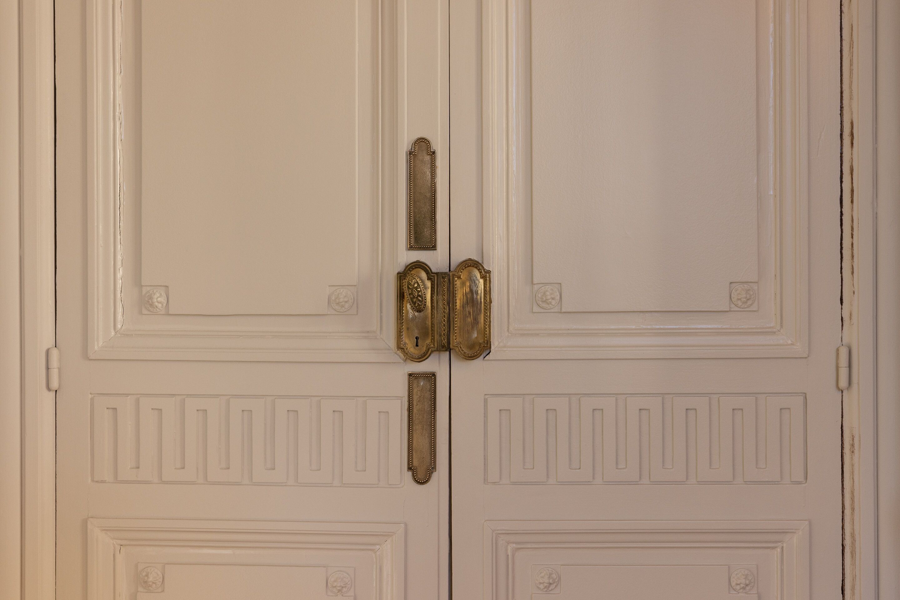 A white double door with a brass handle and a keyhole.