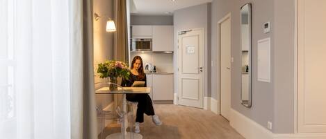 A modern kitchen with a built-in oven and microwave, a dining area with a table and chairs, and a hallway with a door and a mirror.