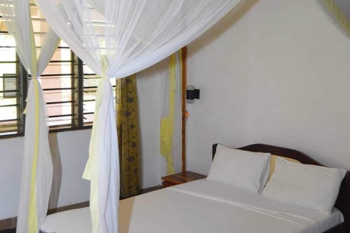 Una cama individual con dosel, una mesita de noche y una lámpara de pared.