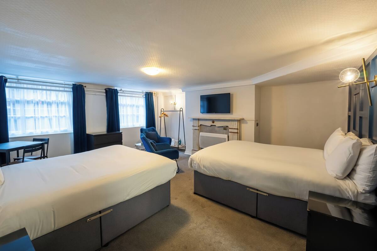 A hotel room with two beds, a TV, a desk, and a chair.