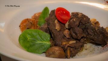 A plate with sliced meat, mushrooms, and a cherry tomato.