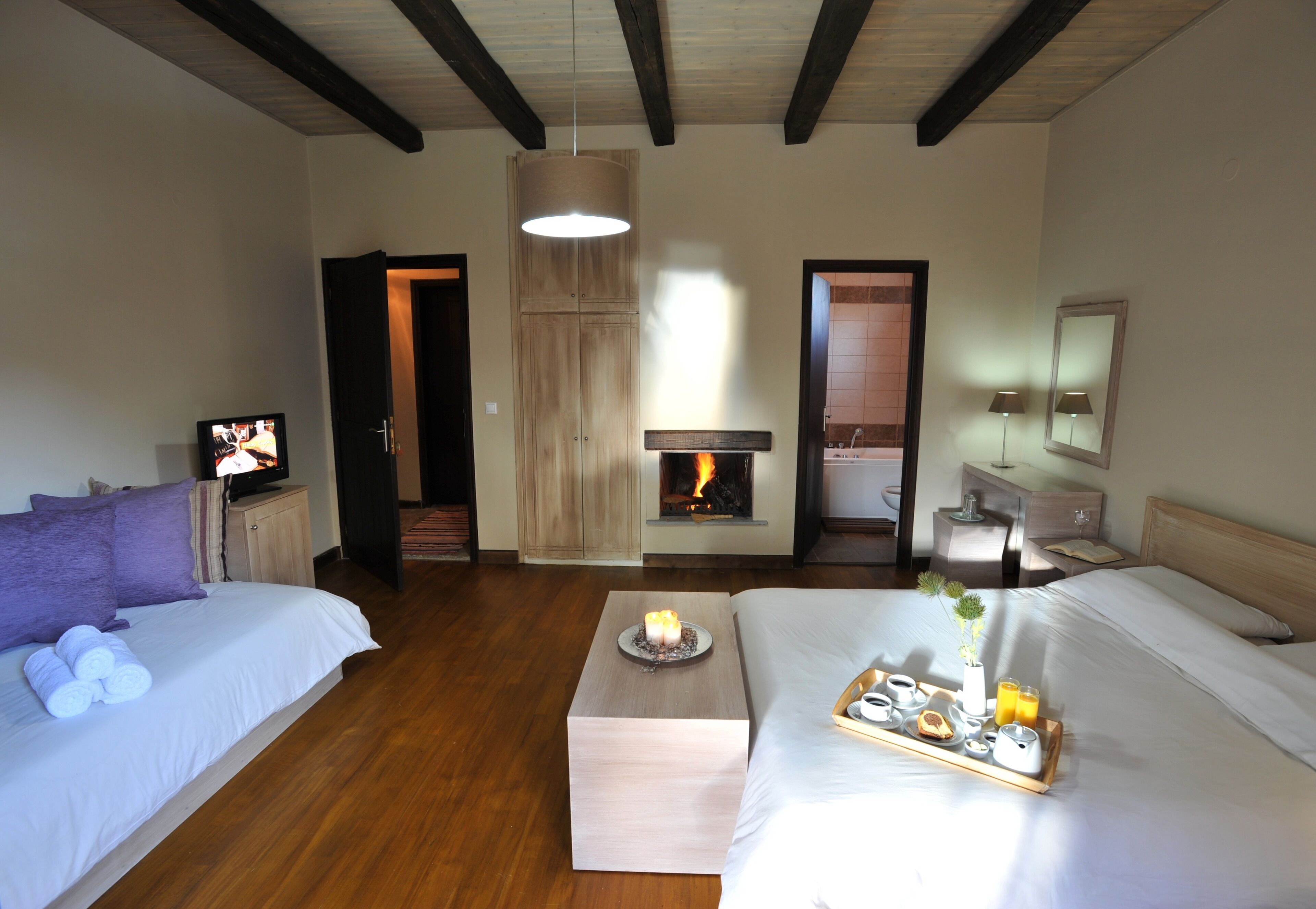A hotel room with a bed, a TV, a fireplace, and a breakfast tray.