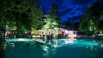 Een buitenzwembad, ligstoelen bij het zwembad