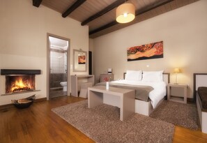 Un dormitorio con chimenea, una cama, mesitas de noche y un cuadro en la pared.
