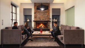 Una sala de estar moderna con chimenea, dos sofás, una mesa de centro y una pared de acento de piedra.