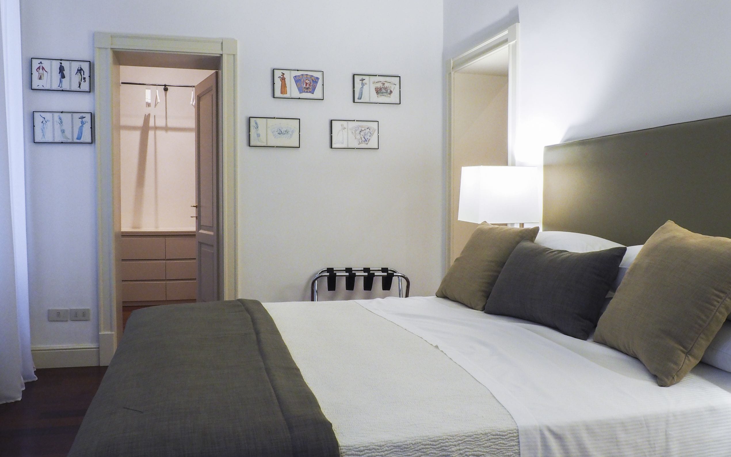 Une chambre d’hôtel comprenant un lit, une lampe de chevet, une chaise et une porte donnant sur une salle de bain.