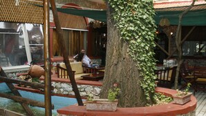 An outdoor seating area with stone walls, wooden furniture, and potted plants. - Lydia Hotel (Kavala)
