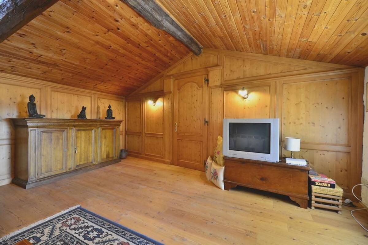 A wooden-paneled room with a fireplace, a television, and a small table with a lamp.