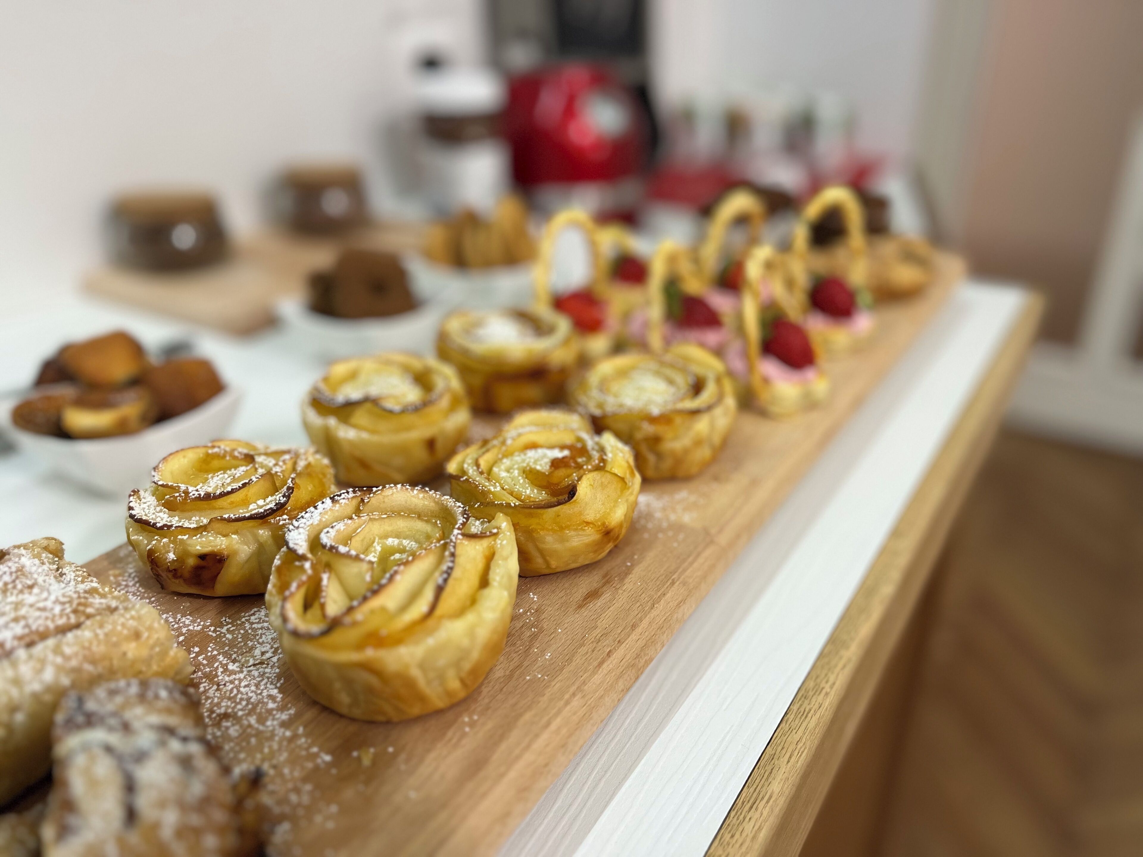 A variety of pastries on a wooden board, including cinnamon rolls and other baked goods.
