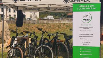 Una tienda de campaña con la marca '24MX' y un cartel que anuncia servicios de alquiler de bicicletas eléctricas.