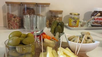 A wooden board with various food items including olives, pickles, cheese, and nuts.