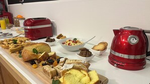 A kitchen counter with a variety of baked goods, including bread and pastries, and a red KitchenAid mixer.