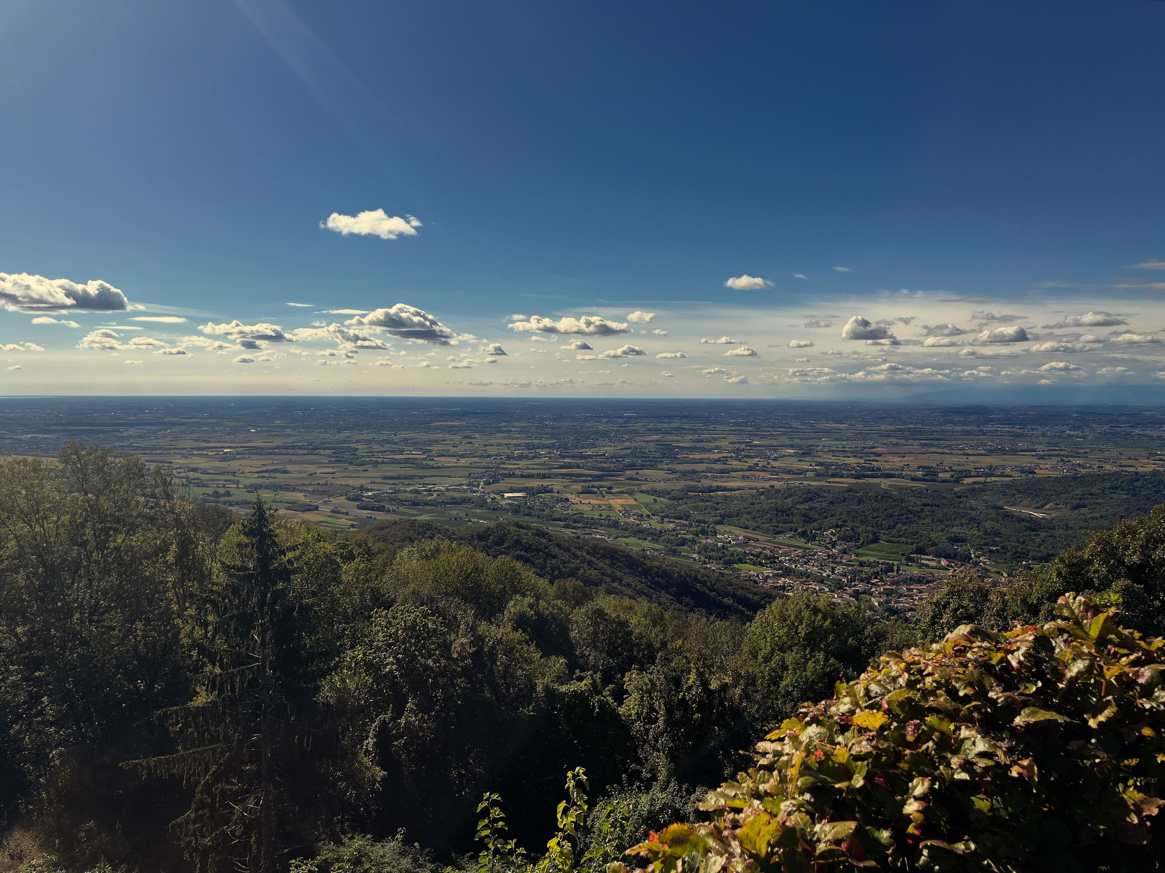 Panoramica di una valle con una cittadina in lontananza, circondata da colline boscose.