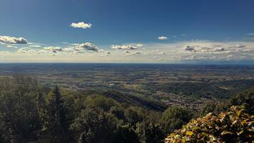 Panoramica di una valle con una cittadina in lontananza, circondata da colline boscose.