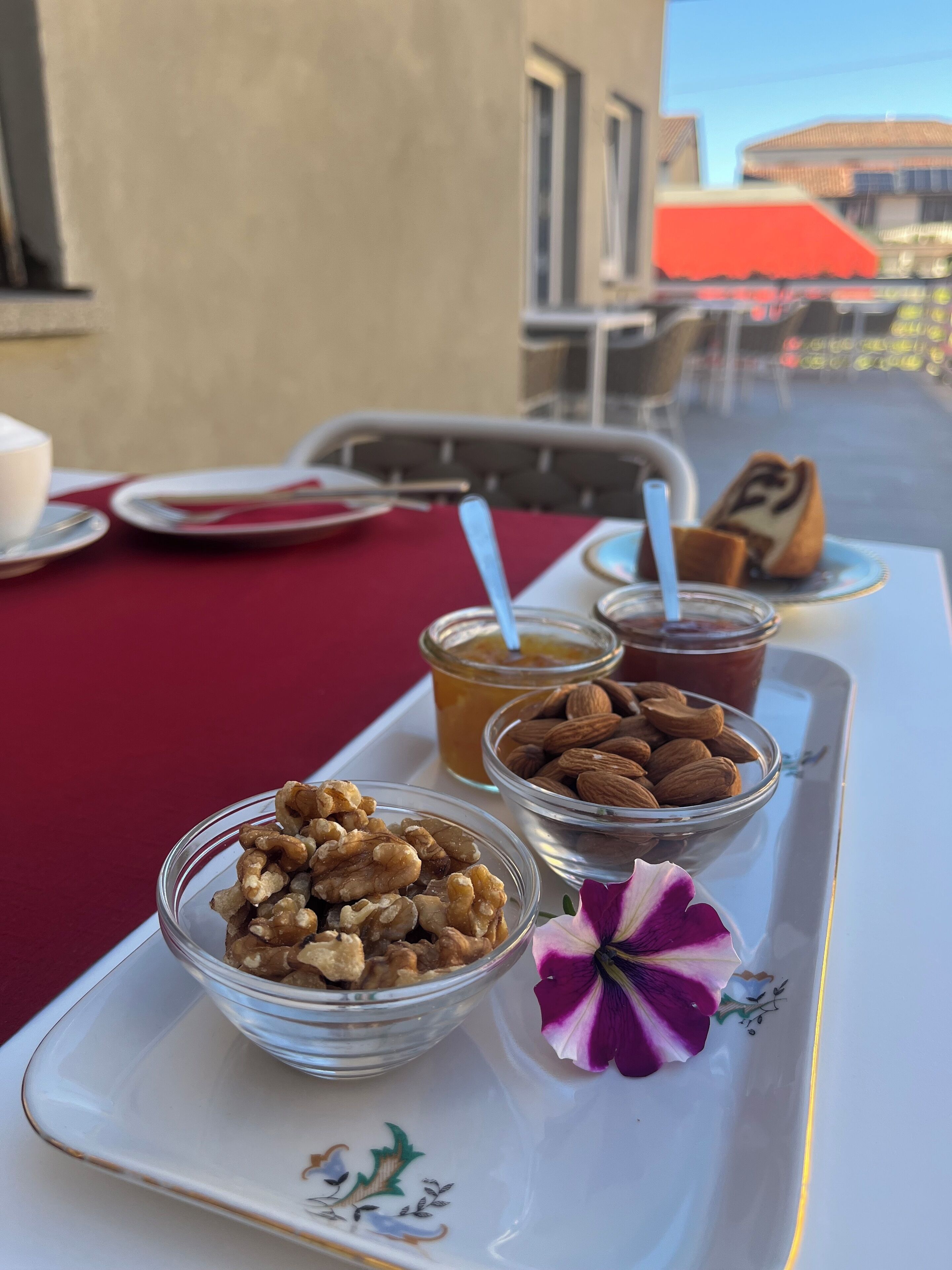A tray with food items including nuts, honey, and a pastry, placed on a table with a red tablecloth.