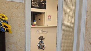A reception area with a sign reading "dai Toscans," a chandelier, a trash bin, and a door leading to a room.