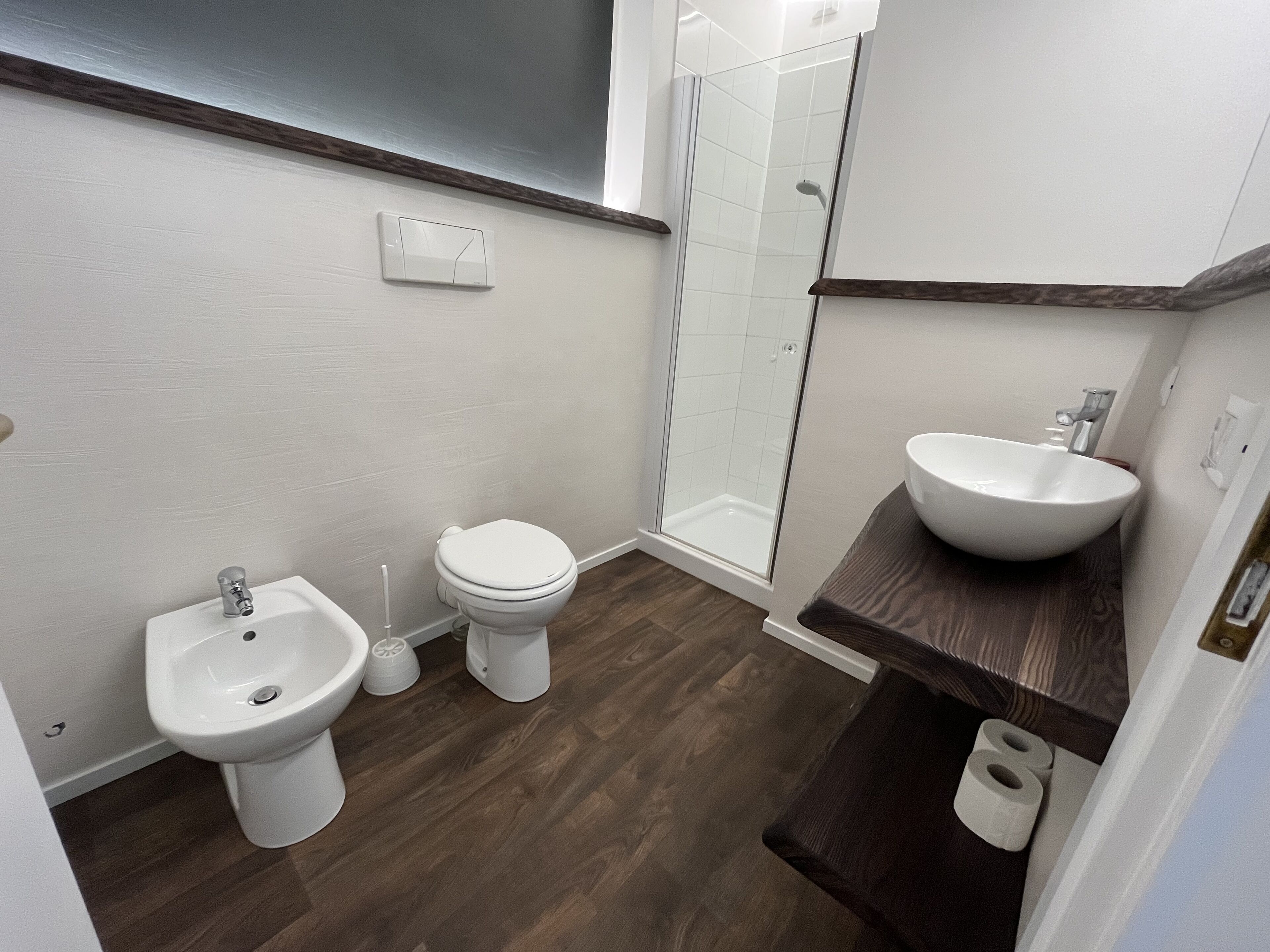 A modern bathroom with a toilet, bidet, and a glass shower enclosure.
