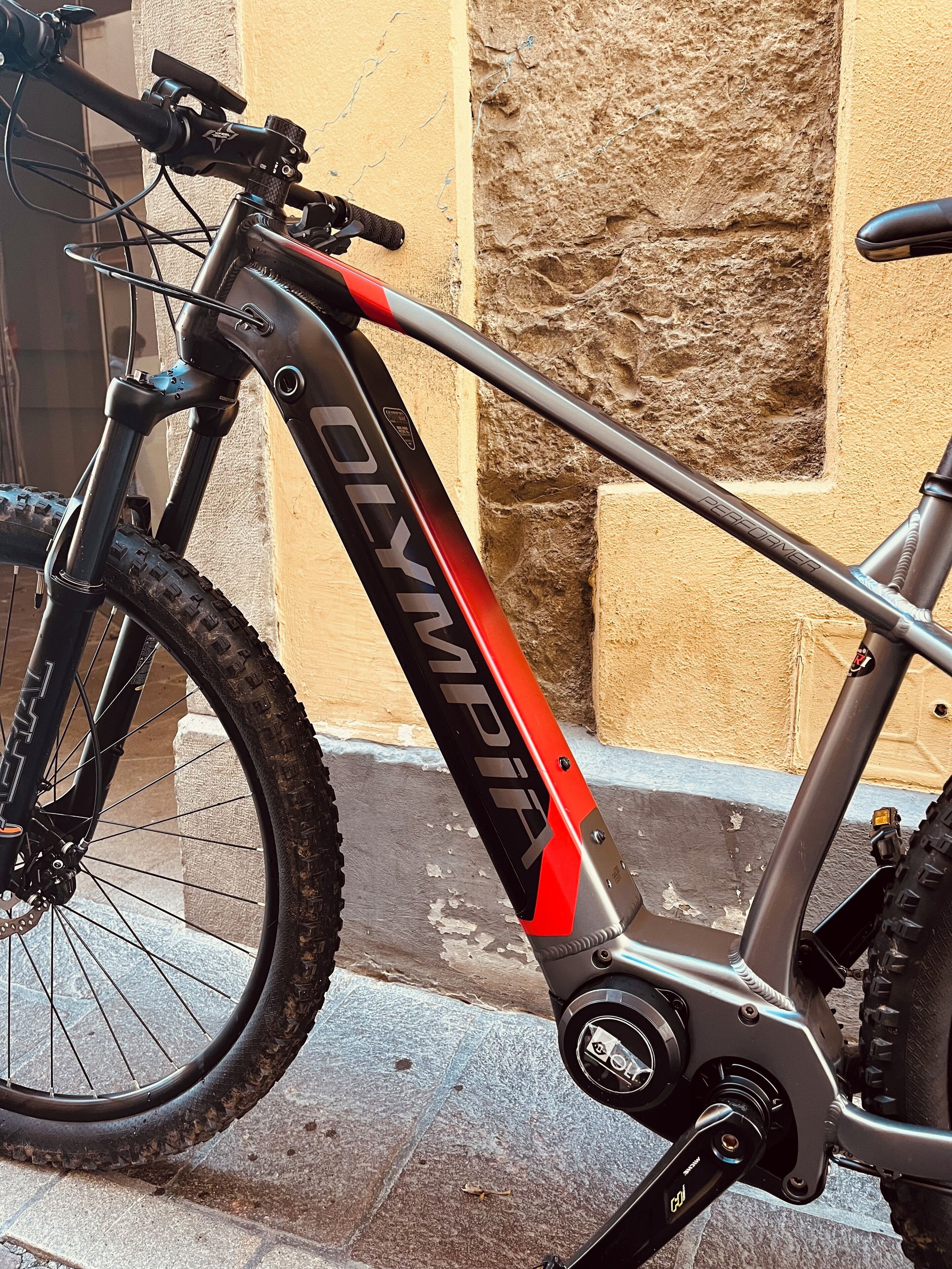 Una bicicleta con la marca "Olympia", horquilla delantera con suspensión y desviador trasero.